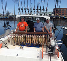 three gentlemen in the back of the boat with fish