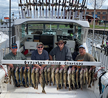 group of guys squatting behind a full board of fish